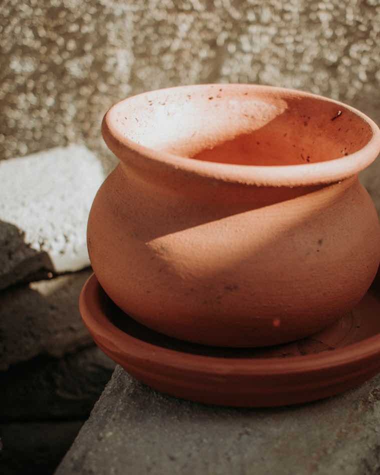 Pequeña vasija de barro cocido sobre superficie de concreto