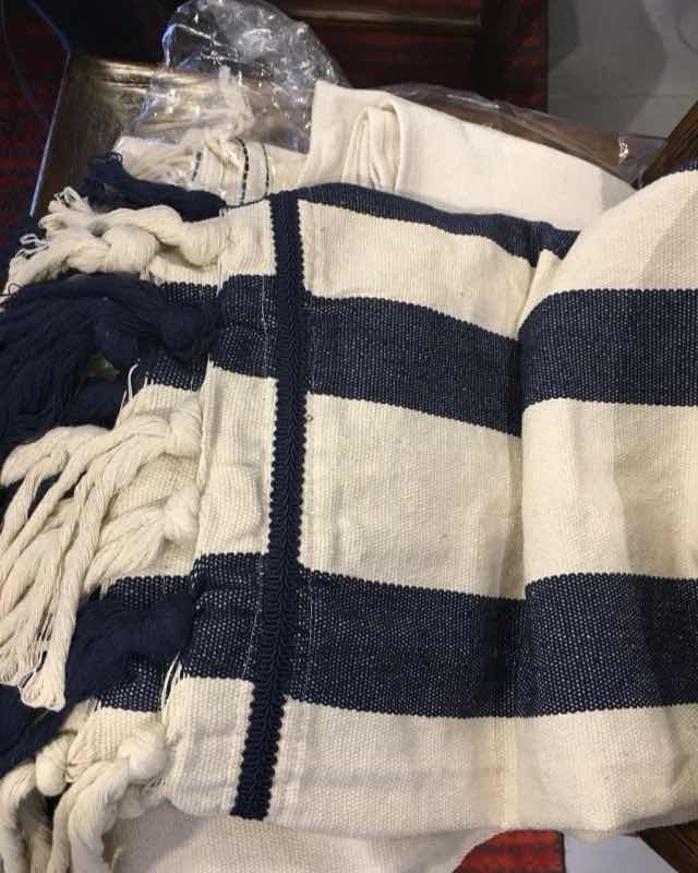 Manta tejida a mano con anchas rayas azul marino sobre fondo crudo y flecos