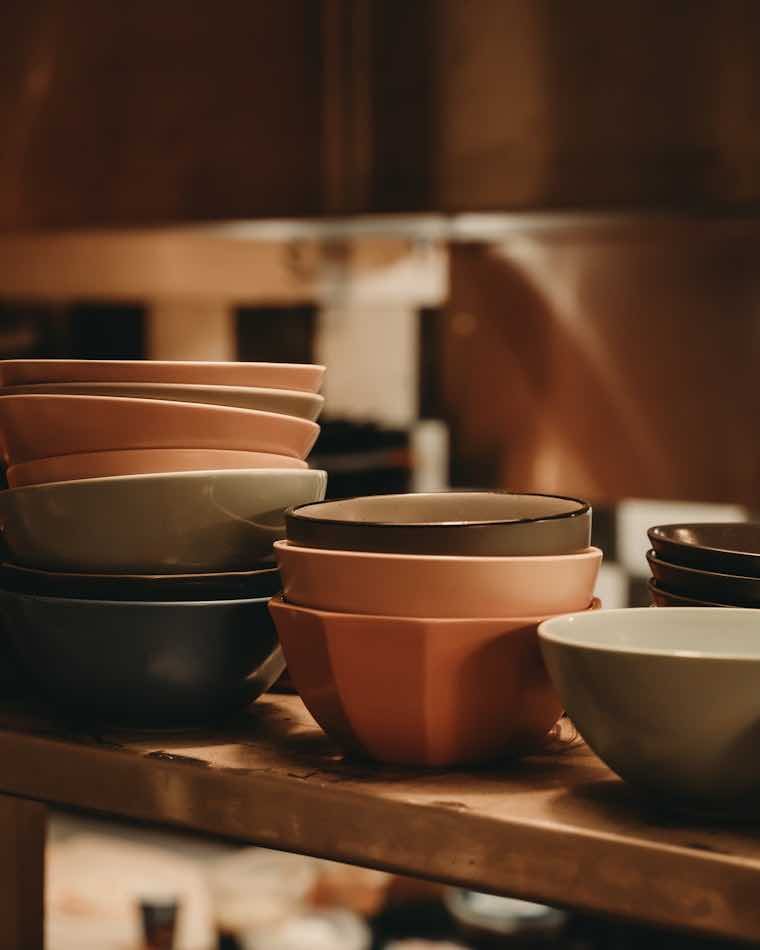 Juego de portavasos artesanales de colores apilados sobre una repisa de madera